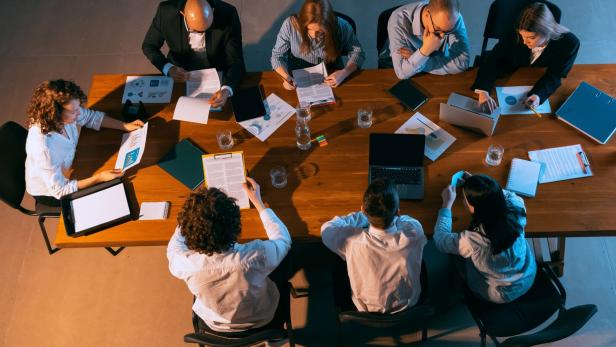 At meeting. Aerial view of young multiethnic people talking, working with colleagues, co-workers at office, indoors. Work, finance, tech concept.
