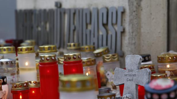 Kerzen und ein Kreuz mit der Aufschrift „Wir vermissen Dich“ vor einem Schulgebäude.