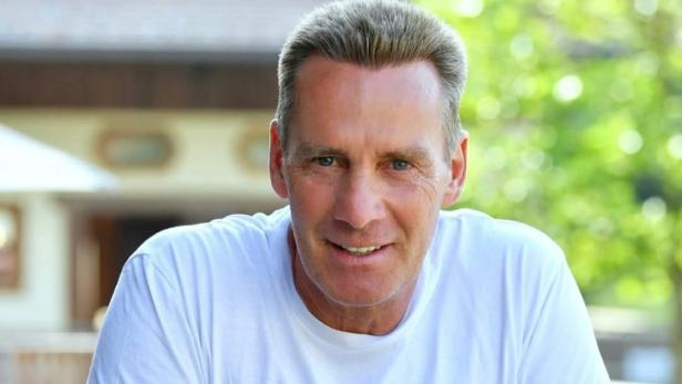 Jürgen Milski posiert lächelnd in einem weißen T-Shirt