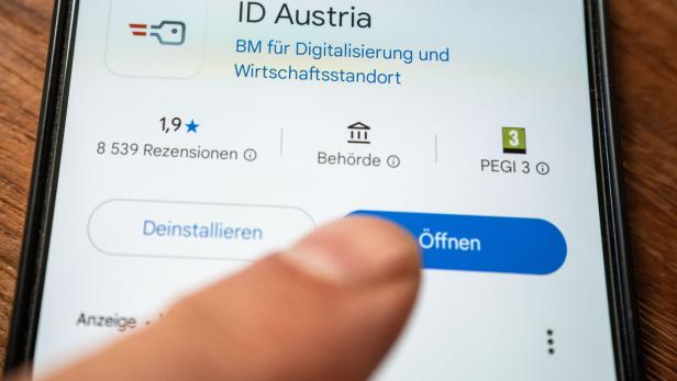 Handy zeigt den App-Store-Eintrag von „ID Austria“, ein Finger berührt die Schaltfläche „Öffnen“.
