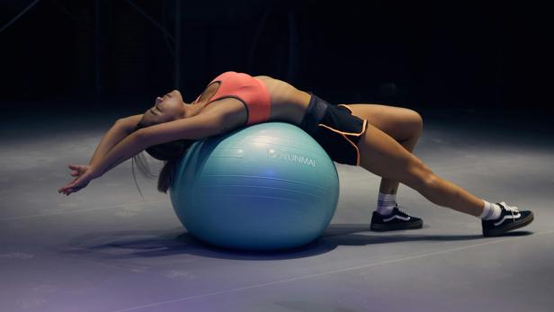 Eine Frau dehnt sich auf einem Gymnastikball.