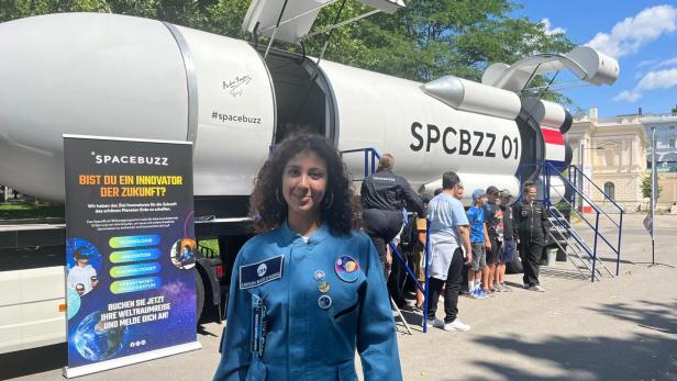 Eine Frau vor einer Spacebuzz-Rakete mit Kindern und einem Werbebanner.