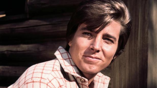 Porträt von Bobby Sherman vor einem Blockhaus.