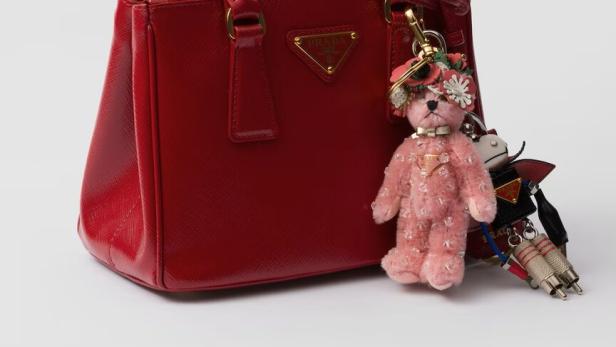 Eine rote Prada-Handtasche mit einem Teddybär- und einem Roboter-Schlüsselanhänger.