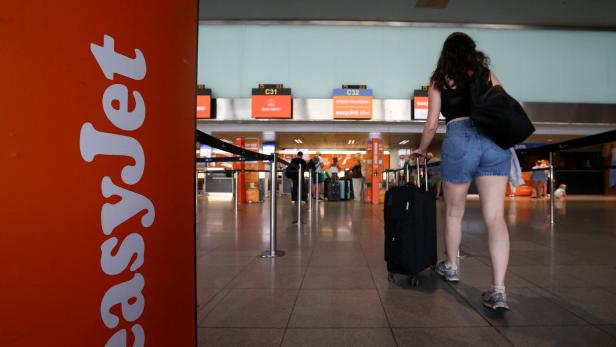 A passenger walks past an Easyjet logo at check-in area during a cabin crew strike