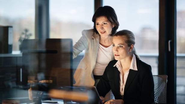 Young and Mature Business Woman Working Late
