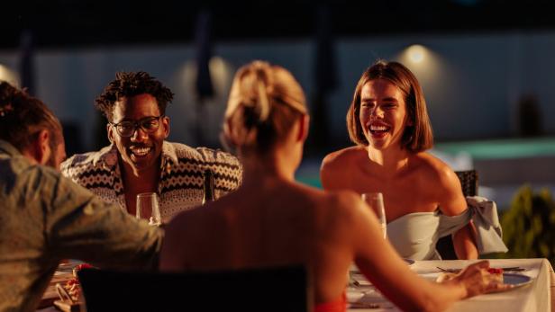 Freunde genießen ein gemeinsames Abendessen in einem luxuriösen Resort.
