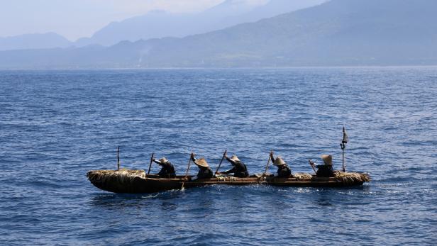 A dugout canoe with four men and one woman paddling is pictured during a crossing across a region of the East China Sea