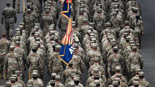 Eine Parade von US-Soldaten in Uniform mit einer Flagge.