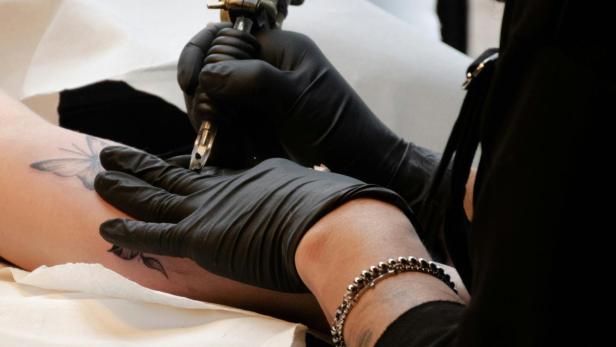 Schmetterlings-Tattoo wird auf Arm gestochen