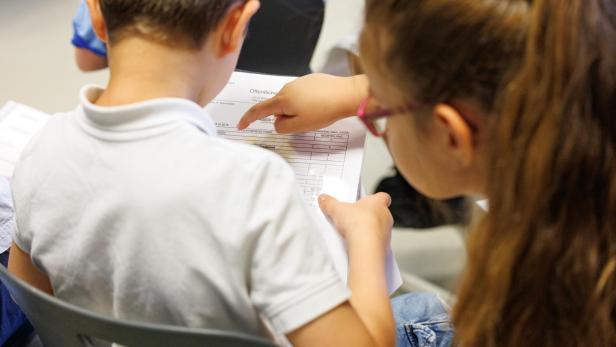Zwei Kinder betrachten ein Formular mit Noten in der Schule.