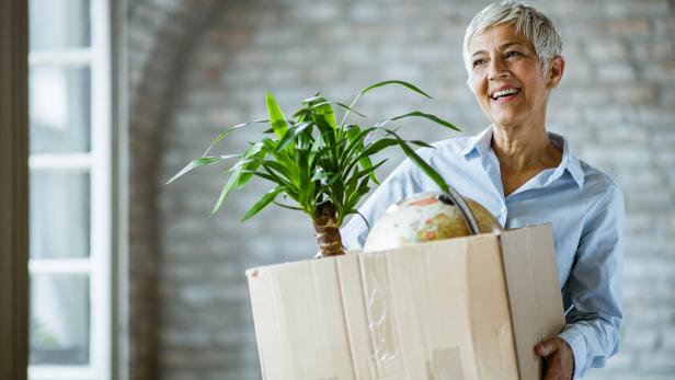 Happy senior businesswoman carrying her belongings after being fired.