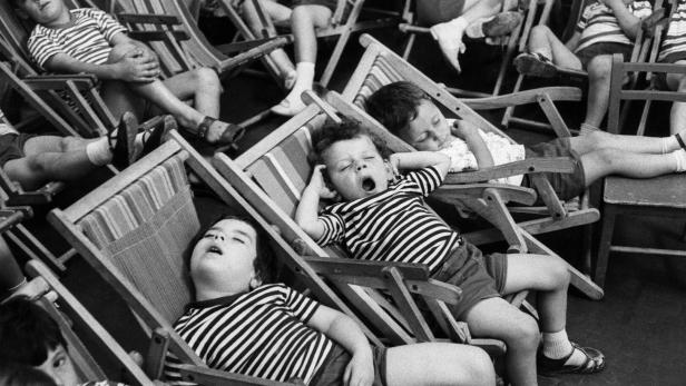 Kinder ruhen sich in Liegestühlen aus, aufgenommen von Henri Cartier-Bresson.