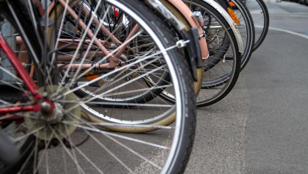 Mehrere Fahrräder stehen nebeneinander auf einem Parkplatz.