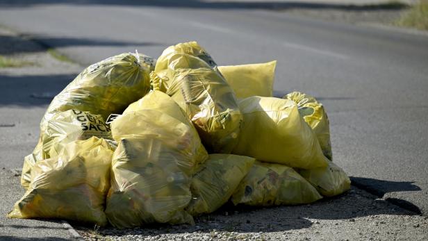 Ein Haufen gelber Säcke liegt am Straßenrand.
