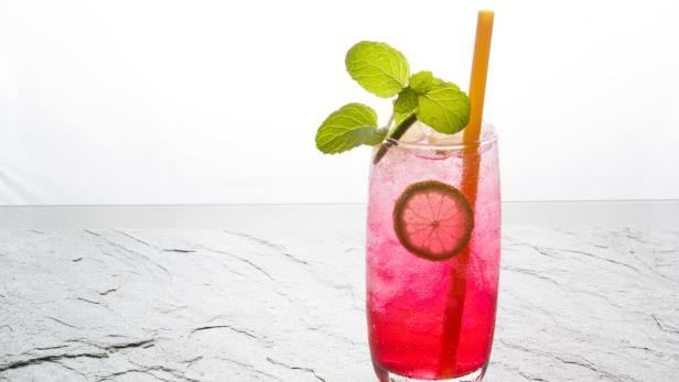 red soda lime drink with lime on stone.