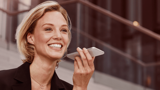 Eine Frau im Businessanzug hält ein Handy in der Hand.