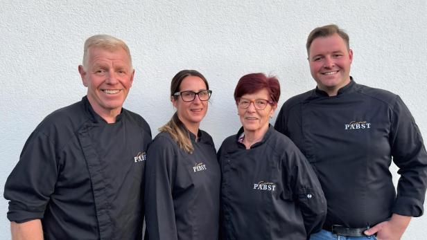 Vier Personen in Kochkleidung lachen in die Kamera.