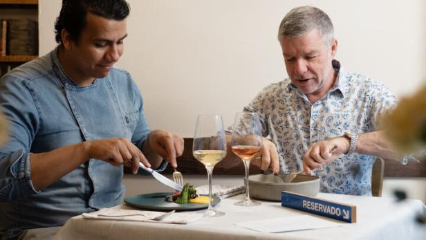 Zwei Männer sitzen an einem Tisch in einem Restaurant und essen.