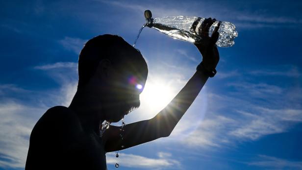 Heatwave in Belgium Ein Bub leert sich Wasser über den Kopf.