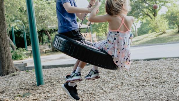 Durch Köln tobt gerade eine Welle der Empörung: Der Begriff "Kinderspielplatz" soll bald ersetzt werden. Zwei Kinder auf einer Schaukel