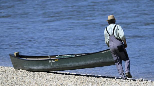 Mann lehnt an Boot am See