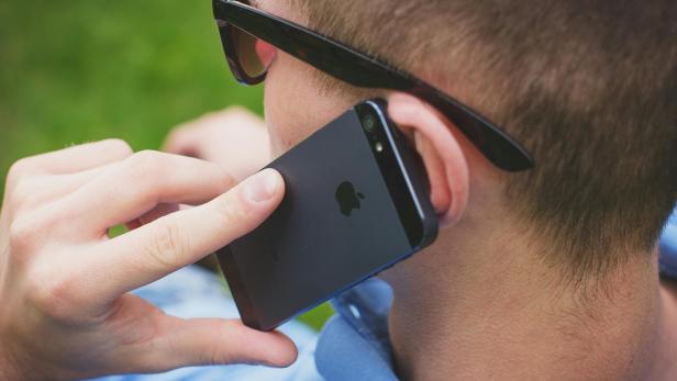 Mann mit Sonnenbrille telefoniert mit iPhone.