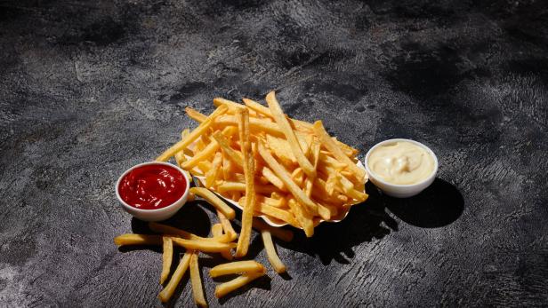 French fries in fryer basket on dark background