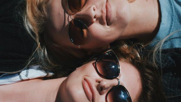 Zwei Frauen liegen mit Sonnenbrille und schauen gegen die Sonne