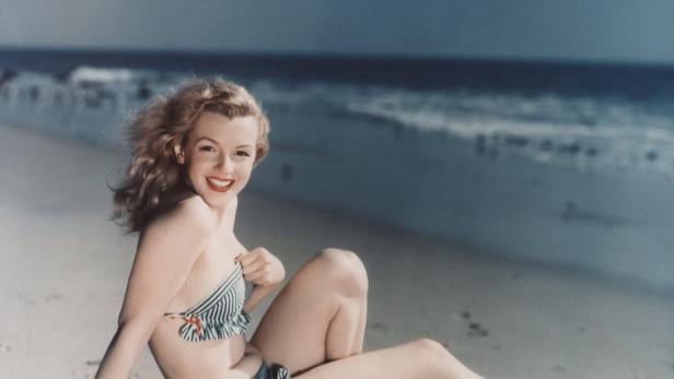 Stilikone Marilyn Monroe posiert im Bikini am Strand.