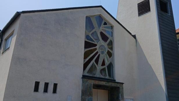 Eine moderne Kirche mit einem Turm und einem Kreuz unter blauem Himmel.