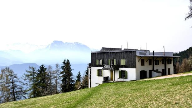 Das Hotel Briol in den Bergen mit Blick auf eine grüne Wiese.