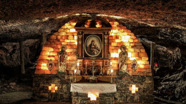 Eine Kapelle in einer Höhle, geschmückt mit Heiligenstatuen und einem Marienbild.