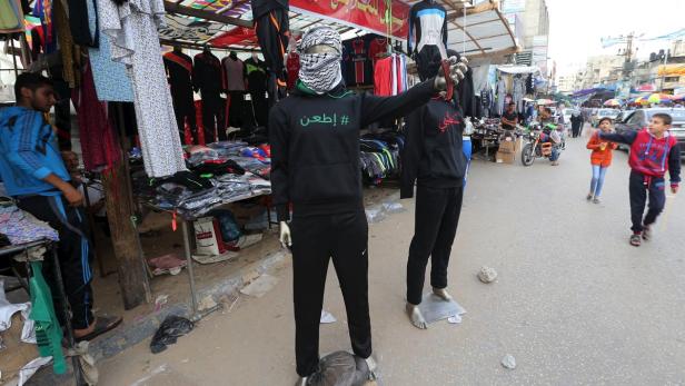 Ein Markt im Freien mit Schaufensterpuppen, die Sportbekleidung und Palästinensertücher tragen.