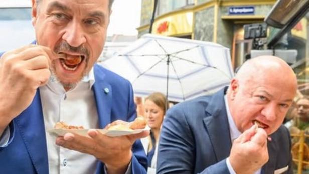 Markus Söder mit Wurst. Im Hintergrund Christian Stocker mit Wurst.