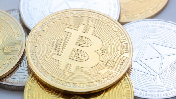 Kryptowährung Mehrere goldene und silberne Bitcoin- und Ethereum-Münzen liegen übereinander.