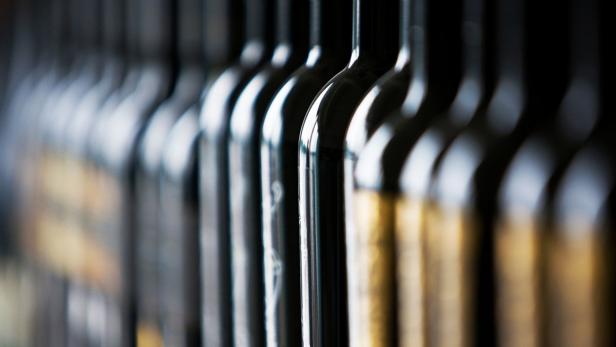 Eine Reihe von Weinflaschen steht nebeneinander.