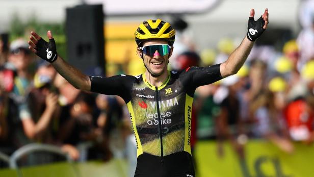 Ein Radrennfahrer jubelt mit erhobenen Armen bei der Tour de France.