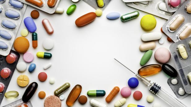 Large group of assorted capsules, pills and blisters making a frame on white background