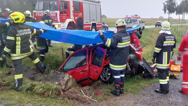 Die Feuerwehr steht rund um ein demoliertes Auto.