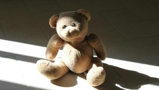 Teddybär sitzt im Sonnenlicht am Boden