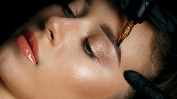 Woman in gloves applying eyebrow tattoo