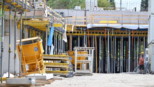 ++ THEMENBILD ++ BAU/ BAUSTELLE/ KONJUNKTUR / IMMOBILIEN Eine Baustelle mit Baumaterialien und Bauarbeitern im Hintergrund.