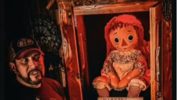 Paranormalforscher Dan Rivera steht neben einer Puppe, die sich in einem Kasten befindet