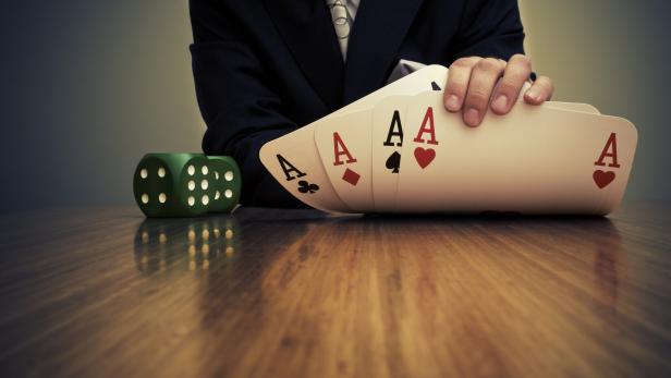 Businessman Sitting at Table Showing Card Hand and Dice