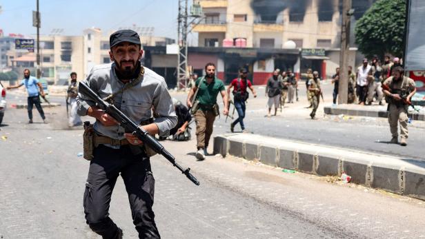 Ein bewaffneter Mann rennt auf einer Straße in Syrien.