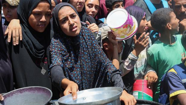 Palestinians gather to receive food from a charity kitchen, amid a hunger crisis, in Nuseirat