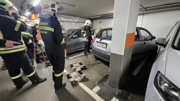 Feuerwehrleute stehen neben Autos in einer Tiefgarage