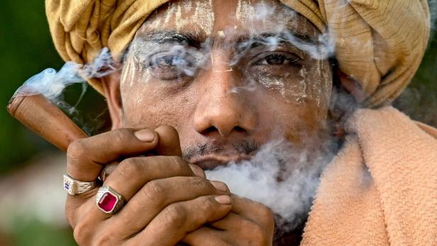 Ein Mann mit Turban und Gesichtsbemalung raucht eine Pfeife.