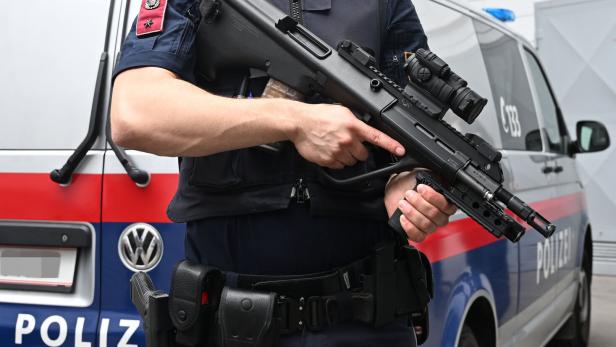 Polizist mit Waffe vor Polizeiauto